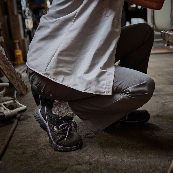 woman bending down wearing black and purple work shoes on the worksite